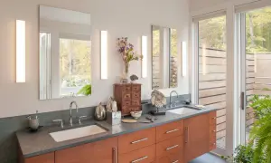 Modern bathroom vanity with two vertical lights over the sinks, reflecting a serene forest view.