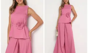 Elegancki różowy komplet z szerokimi spodniami i bluzką z ozdobnym kwiatem. Idealna stylizacja, jak się ubrać na wesele po 50.