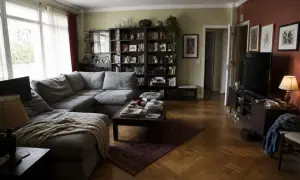 Soggiorno accogliente con divano angolare grigio, libreria piena e parquet. Idee originali per arredare soggiorno con stile.