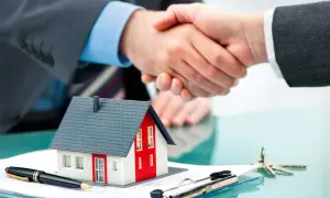 Accordo per un contratto di locazione: stretta di mano su un modello di casa, penna e chiavi.