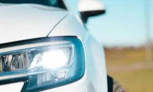 Biały Ford Transit z włączonymi światłami pozycyjnymi. Bezpieczniki świateł pozycyjnych są kluczowe dla sprawnego działania oświetlenia.