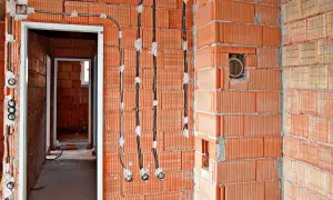Nowe przewody elektryczne prowadzone po ścianie z pustaków ceramicznych, to nowoczesna wymiana instalacji elektrycznej bez kucia.