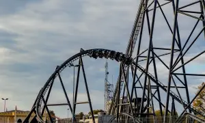 Pasażerowie na wagonikach pędzą po torach najszybszego rollercoastera w Europie, który wznosi się ku niebu.