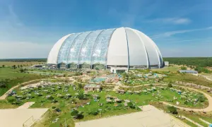 Krausnick tropical island: ogromna hala z basenami i leżakami na trawie, plaża do siatkówki, otoczona zielenią.