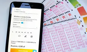 Smartfon z aplikacją do gry w lotto obok kuponów lotto.
