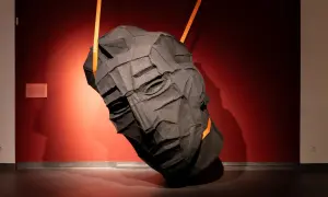 Mroczna, tekstylna głowa wisi na pomarańczowych pasach w muzeum sztuki współczesnej Gdańsk.