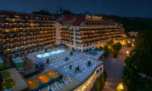 Hotel Gołębiewski Wisła nocą, z podświetlonym basenem, jacuzzi i licznymi leżakami.