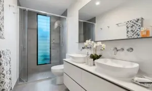 Elegantes baños modernos con ducha, lavabos dobles y ventana azul.