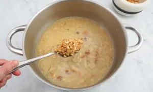 Cuchara con trozos de almendras listas para añadir a la salsa en la olla.