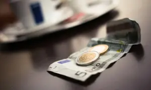 Na stole leży banknot 5 euro i monety. To waluta w Grecji, idealna na kawę.