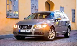 En servad bil, en silverfärgad Volvo kombi, står parkerad på en kullerstensgata framför en gul byggnad med fönster.