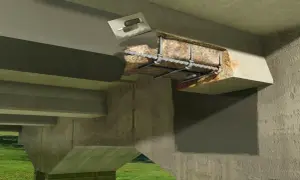 Detalle de reparación estructural de un puente. Se observa el hormigón dañado y la armadura expuesta, con una llana aplicando mortero para la restauración.