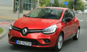 Czerwony Renault Clio 3 1.2 benzyna w ruchu miejskim. Kierowca w okularach przeciwsłonecznych.