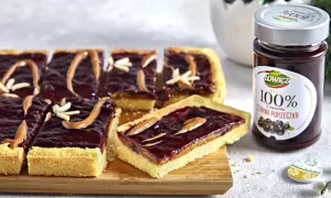 Kawałki mazurka kajmakowego z dżemem z czarnej porzeczki i dekoracjami z kajmaku i migdałów.