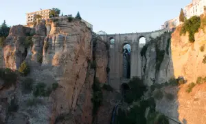 Impresionante puente de piedra sobre un profundo tajo, ideal para rutas por Ronda. Edificios se asoman al abismo.