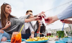 Grupa przyjaciół wznosi toast czerwonym aperitifem, ciesząc się spotkaniem na świeżym powietrzu.