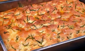 En gyllene focaccia barese med rosmarin och flingsalt i en form. Doftar ljuvligt!