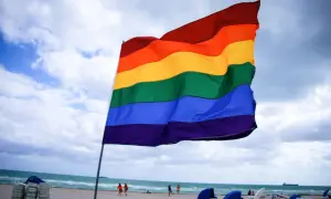 Tęczowa flaga na plaży, symbol akceptacji i wolności, w opozycji do szkodliwej terapii konwersyjnej w Polsce.