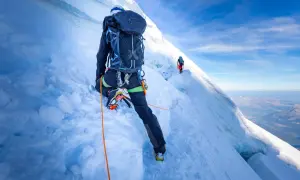 Bergsteiger auf dem Mont Blanc Normalweg, gesichert durch ein Seil, steigen über eisige Hänge.
