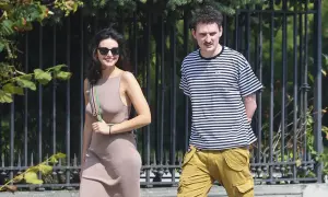 Dawid Podsiadło i jego dziewczyna spacerują w słoneczny dzień. Ona w beżowej sukience, on w bluzie w paski.