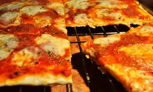 Pyszna pizza na cienkim cieście, z ciągnącym się serem i aromatycznym sosem pomidorowym, prosto z pieca.