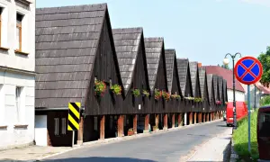Rząd drewnianych domów z charakterystycznymi spiczastymi dachami i kwitnącymi balkonami. Chełmsko Śląskie atrakcje zachwycają unikalną architekturą.
