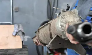 Mechanik trzyma zardzewiały element układu wydechowego, prawdopodobnie filtr DPF. Czas na jego wypalanie lub wymianę.