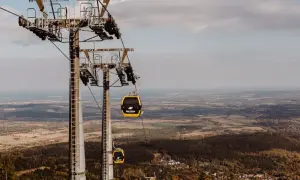 Kolejka linowa, niczym żółty roller coaster, wznosi się nad jesiennym krajobrazem.