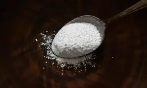 Un cucchiaio pieno di magnesio citrato in polvere bianca, utile per il benessere.