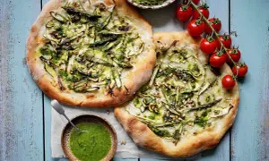 Två läckra, gröna pizzor med sparris och pinjenötter, som en sommar i Rom. Serveras med en skål pesto.