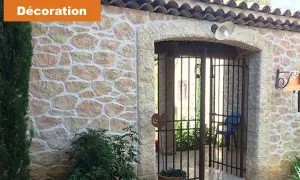 Maison avec un bel enduit pierre apparente, une arche et une grille rouillée.
