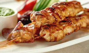 Brochettes de poulet grillées, juteuses et dorées, servies avec une sauce verte et des légumes croquants. Un délice à savourer !