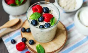 Ein Glas Overnight Oats mit Joghurt, garniert mit frischen Beeren und Minze. Perfekt für ein gesundes Frühstück.
