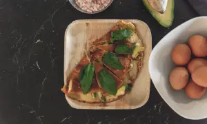 Pyszny omlet z awokado, podany na drewnianej tacce, z jajkami i solą himalajską w tle.