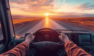 Mani sul volante, un tramonto dorato all'orizzonte. Un viaggio che aiuta a superare la paura di guidare, verso un futuro luminoso.