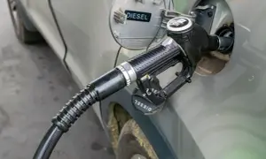 Tankowanie diesla. Zbliżenie na pistolet paliwowy wlewu paliwa samochodu. Informacja o rodzaju paliwa "DIESEL" jest widoczna.