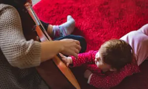 Dziecko słucha piosenek do prezentacji zdjęć z dzieciństwa, gdy ktoś gra na gitarze.