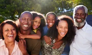 Una familia multigeneracional sonríe y ríe junta al aire libre, disfrutando de actividades de día familiar.