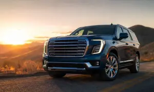 GMC Yukon XL w kolorze granatowym na tle zachodzącego słońca w górach.