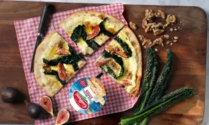 En läcker pizza sverige med fikon, grönkål och valnötter. Serveras på en träskärbräda med färska ingredienser.