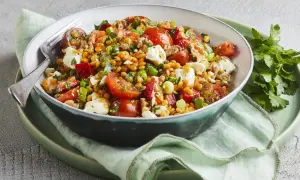 Ein bunter rote Linsen Salat mit Tomaten, Feta und Kräutern, appetitlich in einer Schüssel serviert.