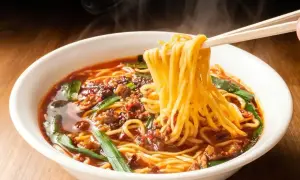 Gorący, parujący ramen z mięsem mielonym i szczypiorkiem. Pałeczki unoszą kłębek żółtego makaronu, zapowiadając, jak smakuje ramen.
