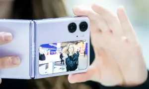 Fioletowy składany telefon z najlepszym aparatem robi zdjęcie młodej kobiecie na targach.