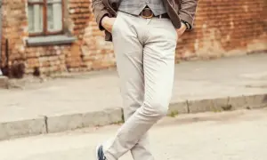 Elegancki mężczyzna w jasnych spodniach i brązowej marynarce. Idealne buty do jasnych spodni męskich to te granatowe, widoczne na zdjęciu.