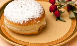 Ein mit Puderzucker bestäubter Krapfen liegt auf einem Teller. Daneben ein Zweig mit Hagebutten. Was ist Hiffenmark?
