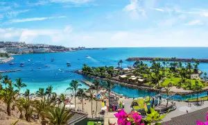 Gran Canaria ciekawostki: malownicza zatoka z plażą, palmami, łodziami i kurortem. Idealne miejsce na wakacje.
