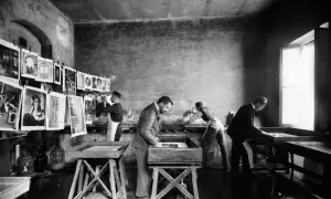 Alessandro Bardi e collaboratori lavorano in un laboratorio di stampa, con stampe appese e vasche per il trattamento.
