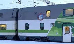 Ein Nachtzug mit Weihnachtsmann-Logo und grüner Landschaftsdekoration im Schnee.