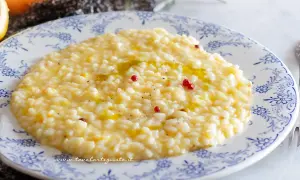 Un cremoso risotto al limone gourmet, guarnito con pepe rosa e un filo d'olio, pronto per essere gustato.