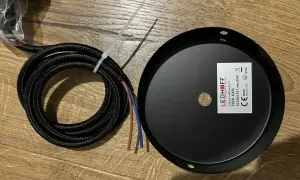 Czarny, pleciony kabel z kolorowymi żyłkami obok czarnej rozety sufitowej LEDHOFF.